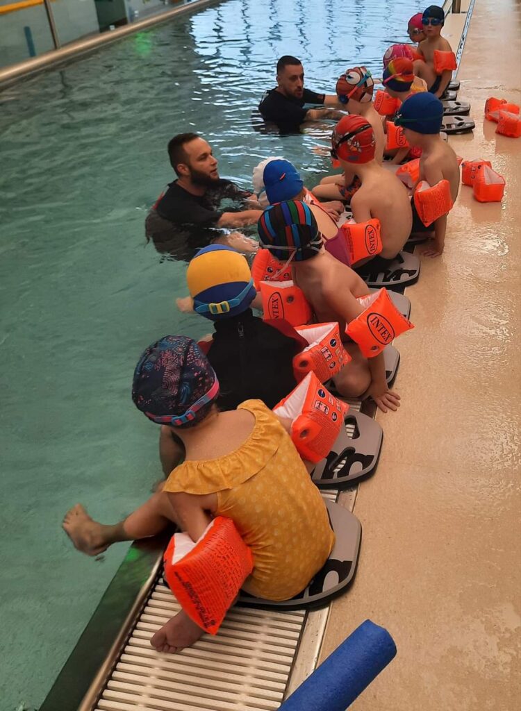Instruktorzy pływania wraz z dziećmi